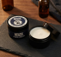 Reuzel Fiber Cream - open potje met witte creme naast gesloten potje op leisteen