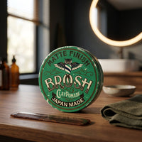 BROSH Matte Finish Clay Pomade - gesloten blik op houten kaptafel met kam en handdoek