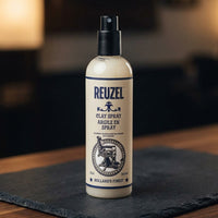 Reuzel Clay Spray 355ml - spuitfles op donkere leisteen in barbershop