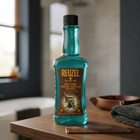 Reuzel Hair Tonic 500ml - fles op houten kaptafel met kam en handdoek